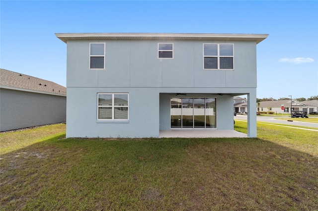 back of property with a lawn and a patio area