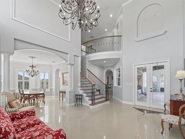 entryway with ornate columns, french doors, a towering ceiling, light tile patterned flooring, and ornamental molding