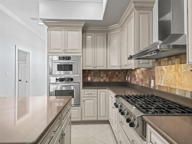 kitchen featuring appliances with stainless steel finishes, wall chimney range hood, ornamental molding, backsplash, and light tile patterned flooring