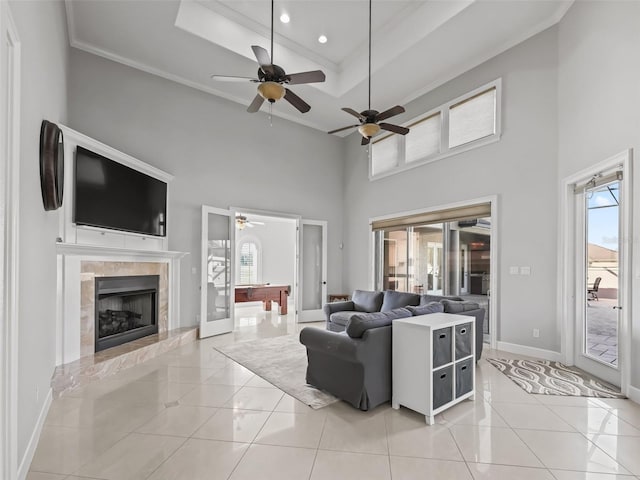 living room featuring crown molding, a towering ceiling, light tile patterned floors, and a tray ceiling