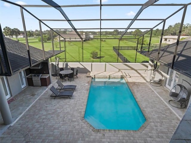 view of swimming pool with a lanai, a patio, an outdoor kitchen, pool water feature, and a yard