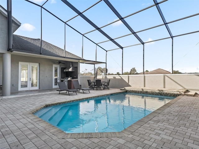 view of swimming pool with glass enclosure, a patio area, ceiling fan, and french doors