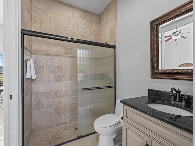 bathroom with tile patterned floors, ceiling fan, toilet, a shower with shower door, and vanity