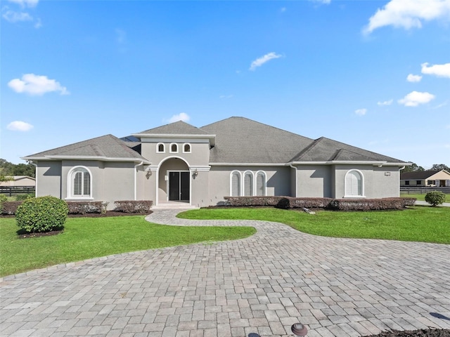 view of front facade with stucco siding, fence, and a front yard