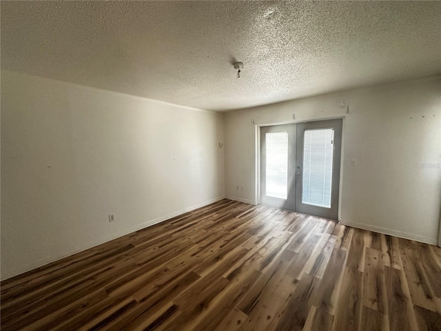 empty room featuring a textured ceiling, dark wood-type flooring, and french doors