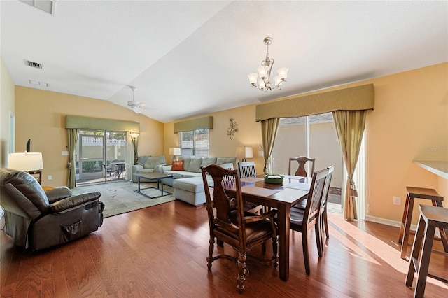 dining area with ceiling fan with notable chandelier, wood-type flooring, and vaulted ceiling