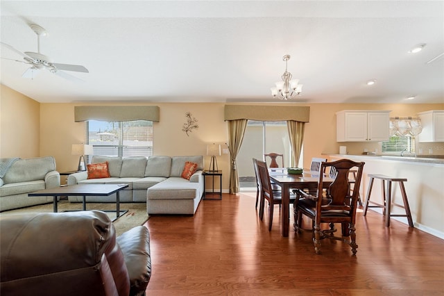 living room with ceiling fan with notable chandelier and dark wood-type flooring