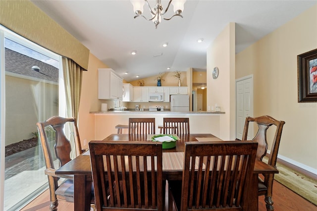 dining space with light wood-type flooring, lofted ceiling, and a notable chandelier