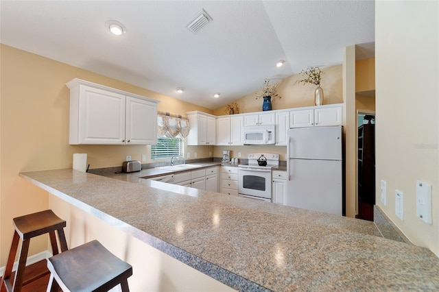 kitchen with white cabinetry, white appliances, kitchen peninsula, and vaulted ceiling