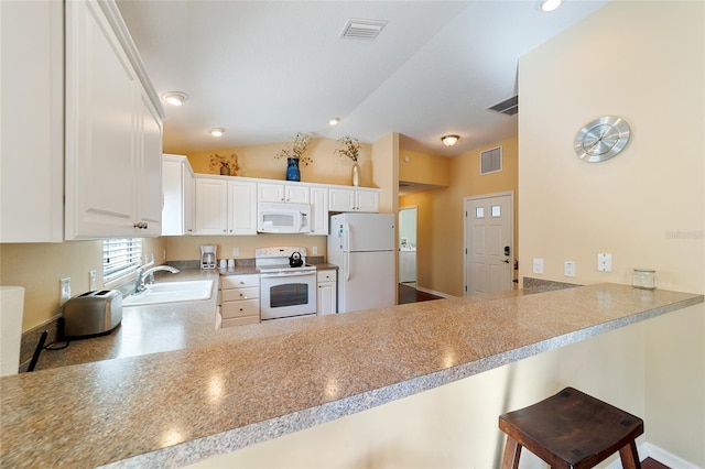 kitchen with white appliances, sink, kitchen peninsula, a kitchen bar, and white cabinetry