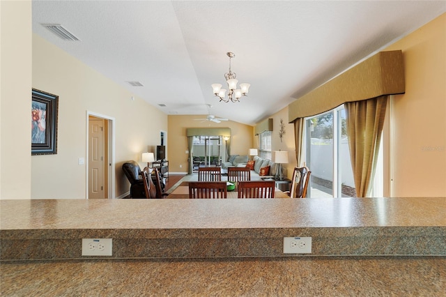 dining room featuring ceiling fan with notable chandelier and vaulted ceiling