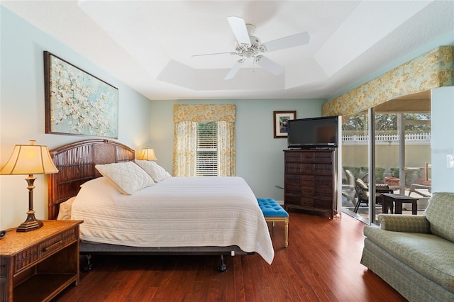 bedroom with ceiling fan, a raised ceiling, and dark wood-type flooring