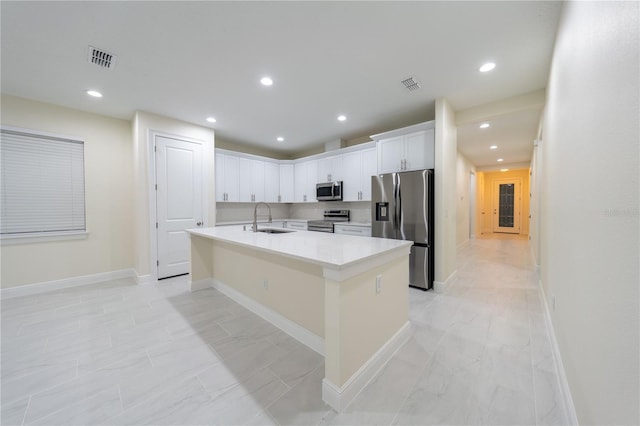 kitchen featuring appliances with stainless steel finishes, sink, white cabinetry, and a center island with sink