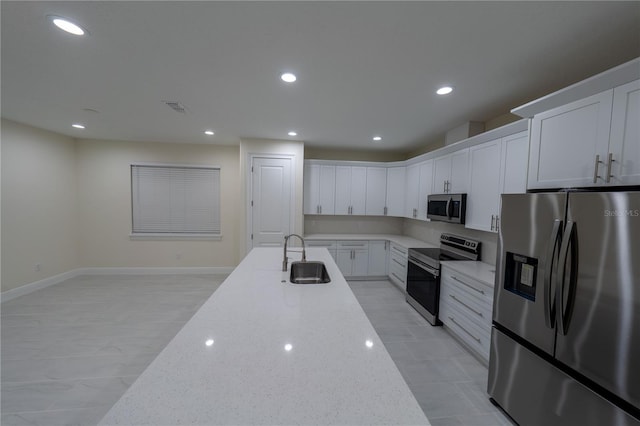 kitchen with light stone counters, sink, white cabinets, and stainless steel appliances