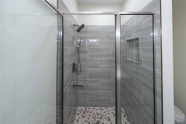 bathroom with a shower with shower door and toilet