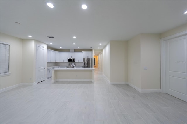 kitchen featuring stainless steel appliances, light hardwood / wood-style floors, white cabinetry, and a kitchen island with sink