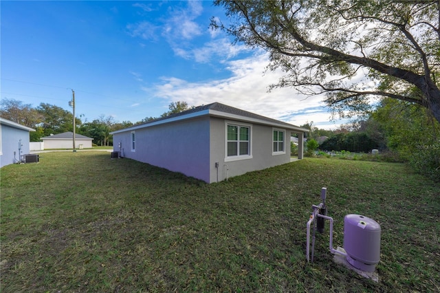 view of side of property with central AC and a yard