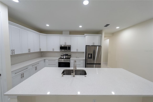 kitchen featuring light stone counters, sink, white cabinetry, and stainless steel appliances