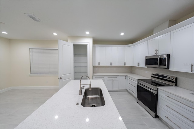 kitchen featuring stainless steel appliances, sink, white cabinets, and light stone countertops