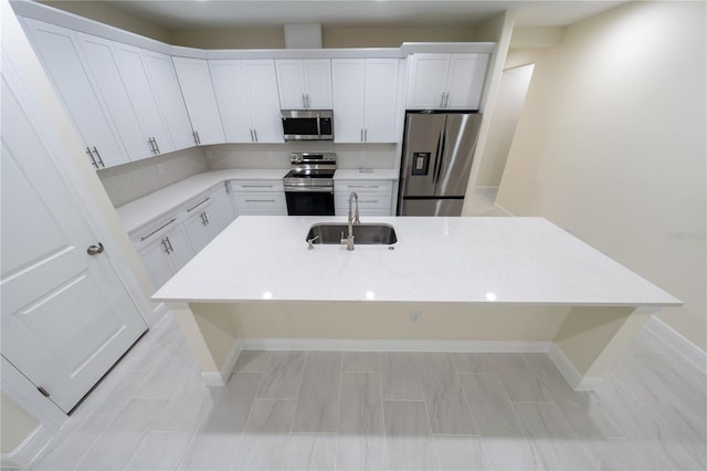 kitchen featuring white cabinets, appliances with stainless steel finishes, sink, and a center island with sink