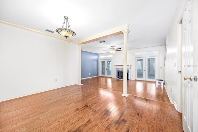 unfurnished living room featuring hardwood / wood-style flooring, ceiling fan, decorative columns, and french doors