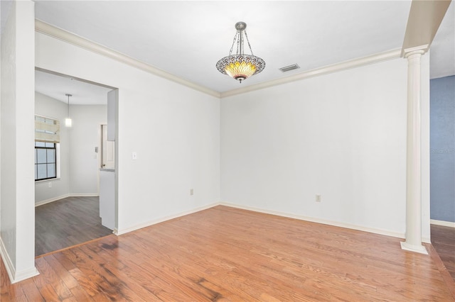 unfurnished room with ornate columns, crown molding, and hardwood / wood-style floors