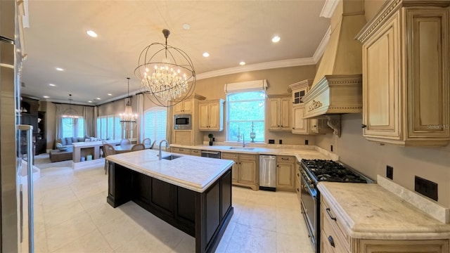 kitchen with light brown cabinetry, stainless steel appliances, sink, decorative light fixtures, and a center island with sink