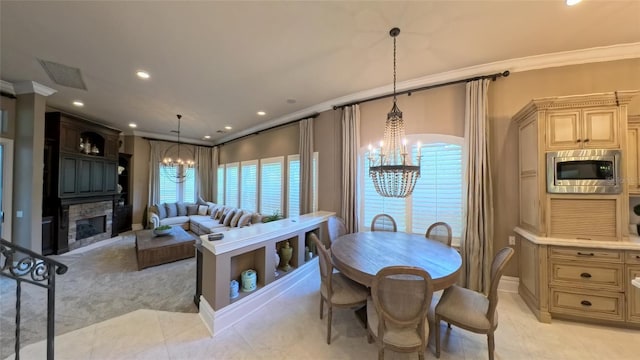 dining area featuring a stone fireplace, light tile patterned floors, a chandelier, and ornamental molding