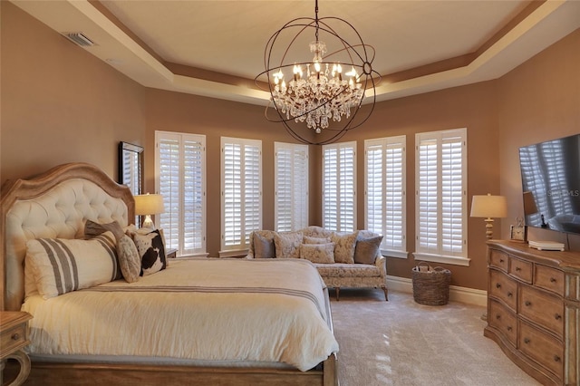 carpeted bedroom with an inviting chandelier, a tray ceiling, and multiple windows