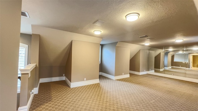 bonus room featuring a textured ceiling and light colored carpet