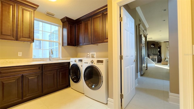 laundry area with crown molding, cabinets, sink, and washing machine and dryer