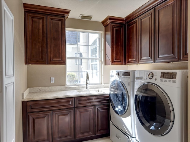 laundry room featuring washing machine and clothes dryer, sink, and cabinets