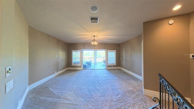 carpeted empty room featuring a notable chandelier