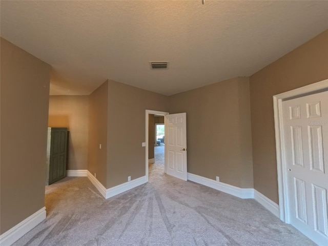 empty room with a textured ceiling and light carpet