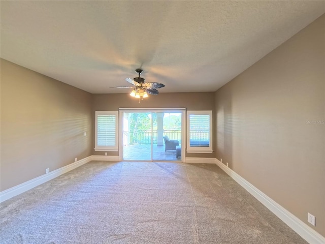 empty room with carpet flooring, ceiling fan, and a textured ceiling