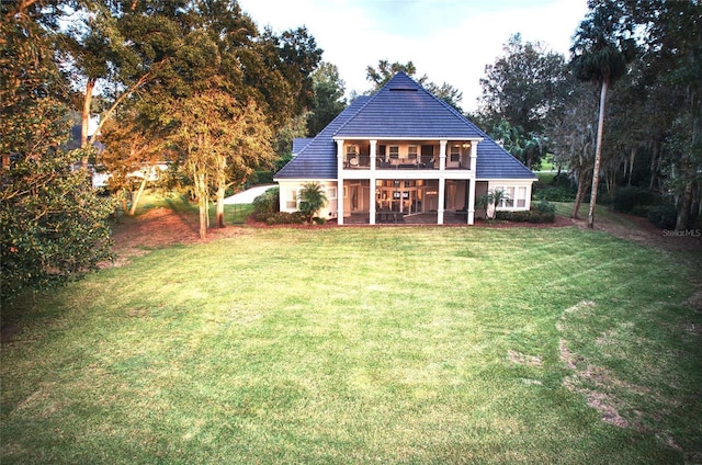 back of house with a balcony and a lawn