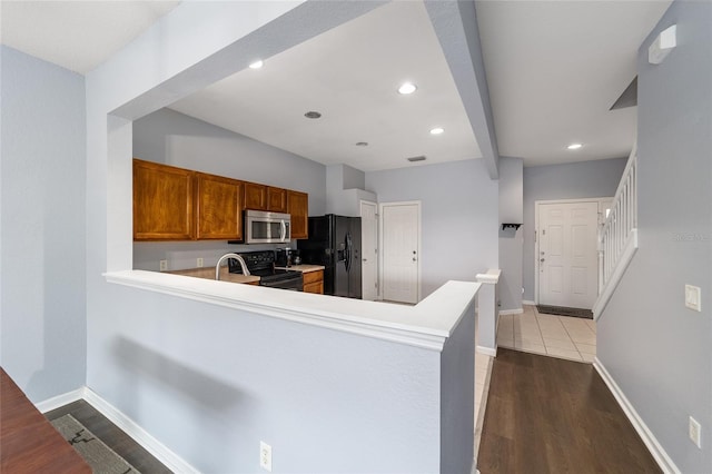 kitchen with kitchen peninsula, sink, black appliances, and light hardwood / wood-style floors