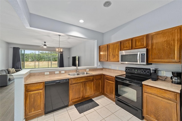 kitchen with sink, kitchen peninsula, light tile patterned floors, black appliances, and ceiling fan with notable chandelier