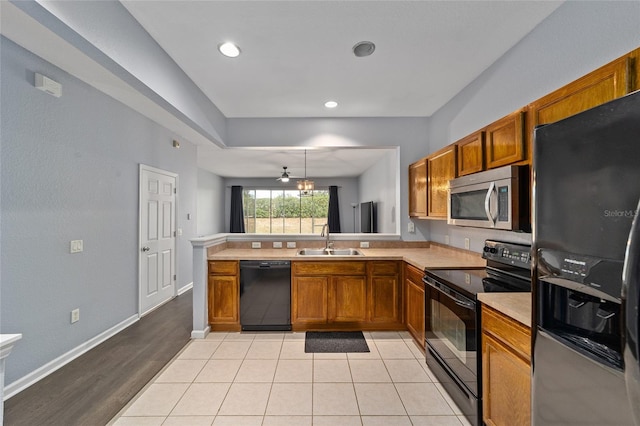 kitchen with black appliances, sink, ceiling fan, light wood-type flooring, and kitchen peninsula