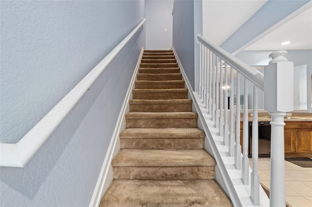 stairway featuring tile patterned floors and ornate columns