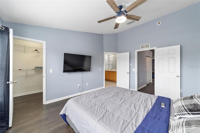 bedroom with ceiling fan, dark hardwood / wood-style flooring, a walk in closet, and a closet