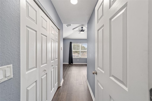 hallway with a textured ceiling and dark hardwood / wood-style flooring