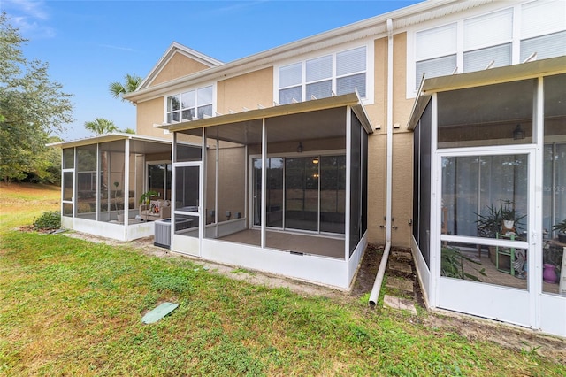 rear view of property featuring a sunroom, central air condition unit, and a lawn