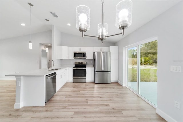 kitchen with kitchen peninsula, appliances with stainless steel finishes, sink, pendant lighting, and lofted ceiling