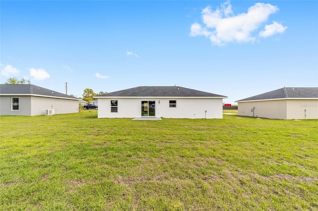 back of property featuring a lawn and stucco siding