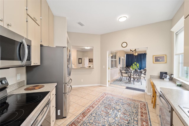 kitchen with light tile patterned floors, appliances with stainless steel finishes, and a healthy amount of sunlight