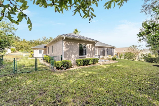 back of house featuring a lawn and a sunroom