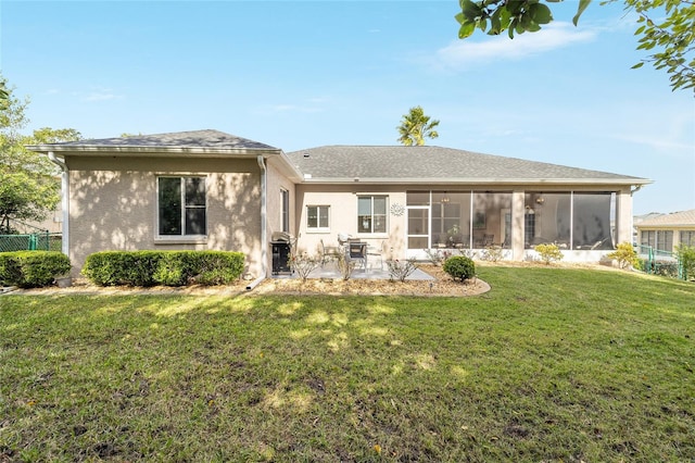 rear view of property with a patio area, a sunroom, and a lawn