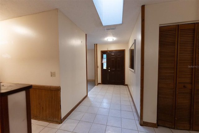 corridor featuring a skylight and light tile patterned flooring