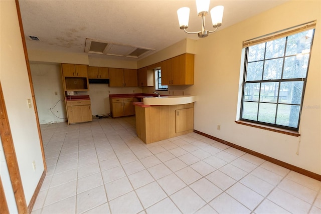 kitchen with kitchen peninsula, a textured ceiling, light tile patterned floors, decorative light fixtures, and a chandelier